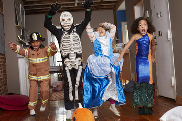 Children in Halloween costumes jumping for joy