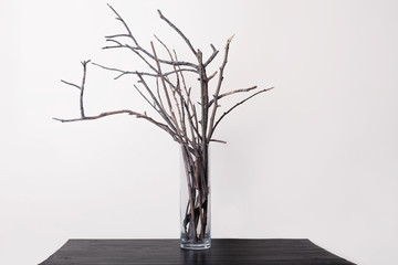 branch in the transparent vase on a wooden table and a light background