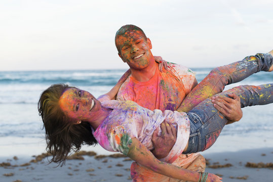 Caucasian couple splattered with paint powder on beach