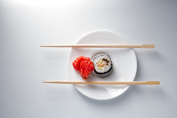 Sushi roll on small plate with chopsticks