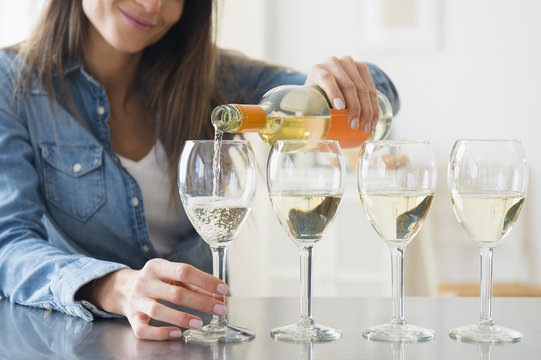 Woman pouring white wine in wine glasses