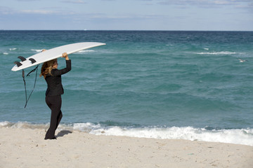 Naklejka premium Business Metaphor: Working Vacation Beautiful business woman in business suit posing on a surfboard 