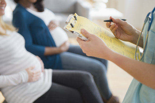 Nurse making medical chart for pregnant woman in hospital