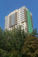 Fototapeta na wymiar Facade of multistory buildings and green trees. Building