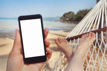 mobile application for travels, hand holding smart phone with white screen on the beach