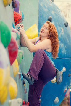 Redhead Woman Indoor Rock Climbing. Colorful Climbing Wall Strong Young Woman