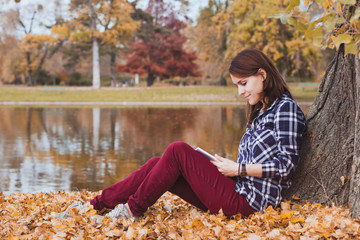 literature, young beautiful woman reading book in autumn park near the lake