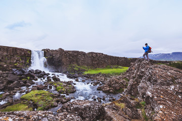 backpacker traveler taking photo of waterfall with mobile phone