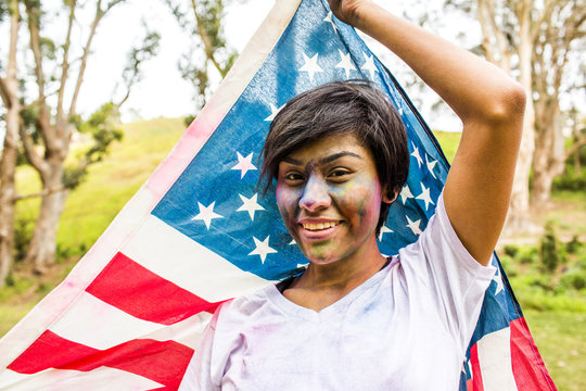 Hispanic woman covered in pigment powder holding American flag