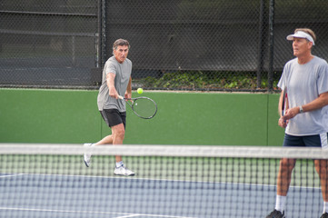 Tall Baby Boomer hitting a backhand return of serve. 