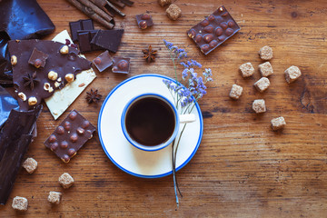 cup of coffee and different kinds of handmade chocolate, top view on wooden background in cafe