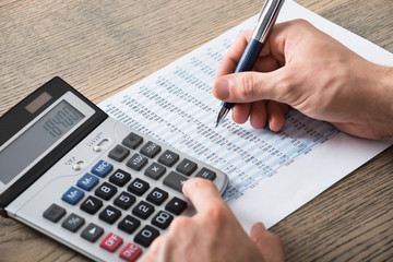Businessman Analyzing Accounting Document With Calculator