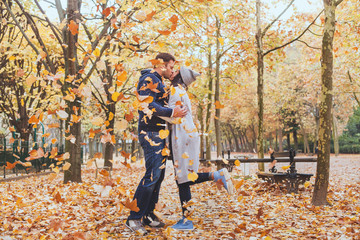 autumn kiss, young loving couple in the park with falling leaves