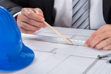 Male Architect Hand Using Pencil And Ruler On Blueprint