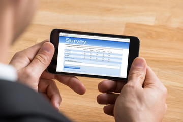 Businessman Filling Online Survey On Mobile Phone