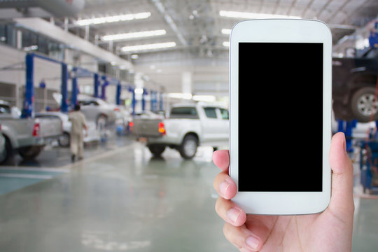 hand hold smartphone with car repair service center background