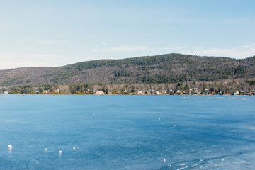 Color DSLR stock image of a frozen Lake George, with lake houses on the shore and Adirondack Mountains in background. Horizontal with copy space for text
