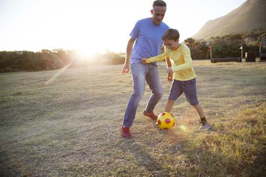 Caucasian father and son playing soccer in field - Powered by Adobe