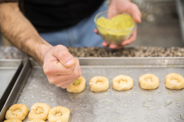 Hands baking dough with rolling pin on wooden table