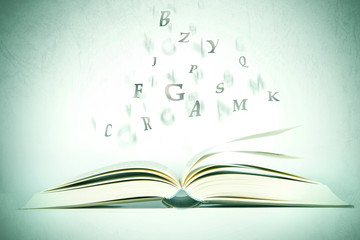 opened book with alphabet letter flying out of pages