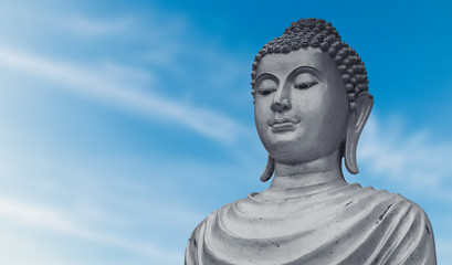 Obraz premium Portrait of old buddha statue on blue sky background at public temple in Thailand.