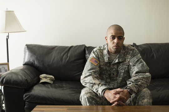 Mixed race soldier sitting on living room sofa