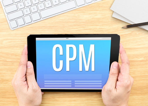 Hand holding tablet with CPM (Cost per mille)  word on wood tabl