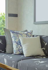 Decorative pillows setting on gray sofa with wooden base in living room