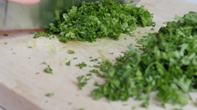 Fresh parsley vegetable plant cutting with knife on smaller pieces 4K 3840X2160 UltraHD footage - Petroselinum crispum plant on cutting board 4K 2160p UHD video 