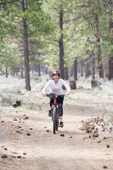 Obraz premium Woman riding mountain bike on trail in forest