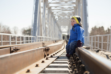 Young boy walking along train tracks