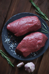 Fresh uncooked asado beefsteaks on a basalt plate, above view