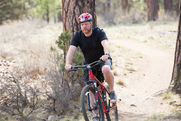 Man riding bike on dirt trail in woods