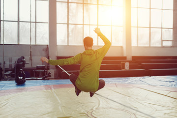 Man slacklining walking and balancing on a rope, slackline in a sports hall