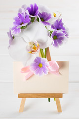 Bouquet of violet primroses with orchid and paper greeting card