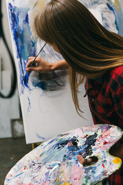 Young woman painting pictures in a workshop