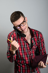 young man talking on the landline telephone and writing something in note, great deal, win