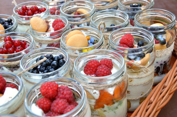 Sweet and healthy dessert: many glasses filled with cream and tiny colorful fruit