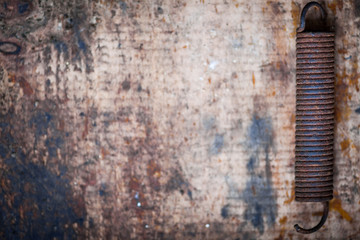 Rusty spring on wooden plank