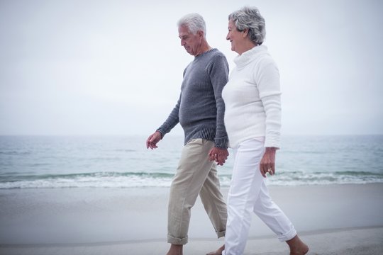 Senior couple holding hands and walking on the beach