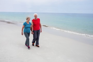 Senior couple holding hands and walking on the beach