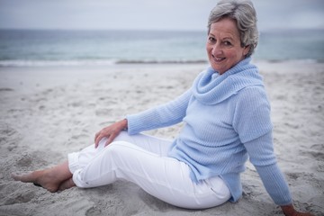 Fototapeta na wymiar Happy senior woman sitting on beach