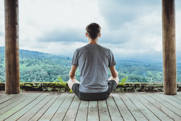 Young fashionable man meditating in the gazebo on the background