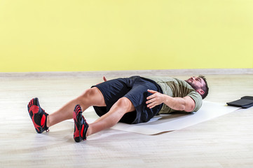 Young man at gym, exercising with friction pads.
