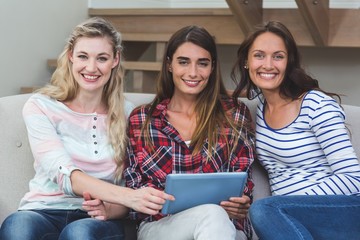 Friends sitting on sofa and using digital tablet