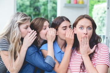 Women in a row whispering secrets in their friends ears