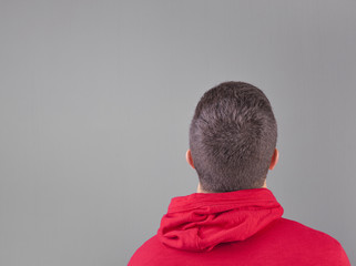 Back view of a young man wearing a red sweatshirt on grey backgr