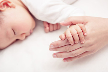 Hand the sleeping baby in the hand of mother close-up (Soft focu