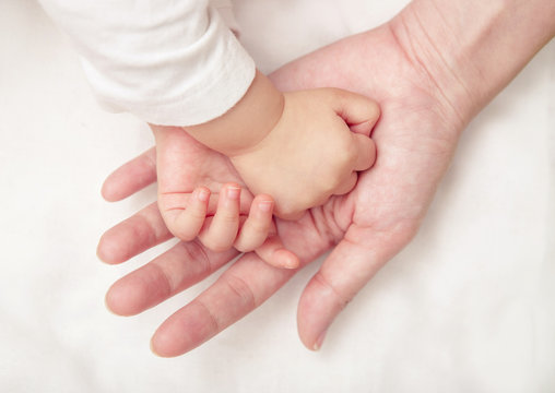Baby hand gently holding adult's finger (Soft focus and blurry)