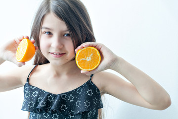 Little girl lying on the floor and holding a slice of orange as the orange glasses. Summer mood.